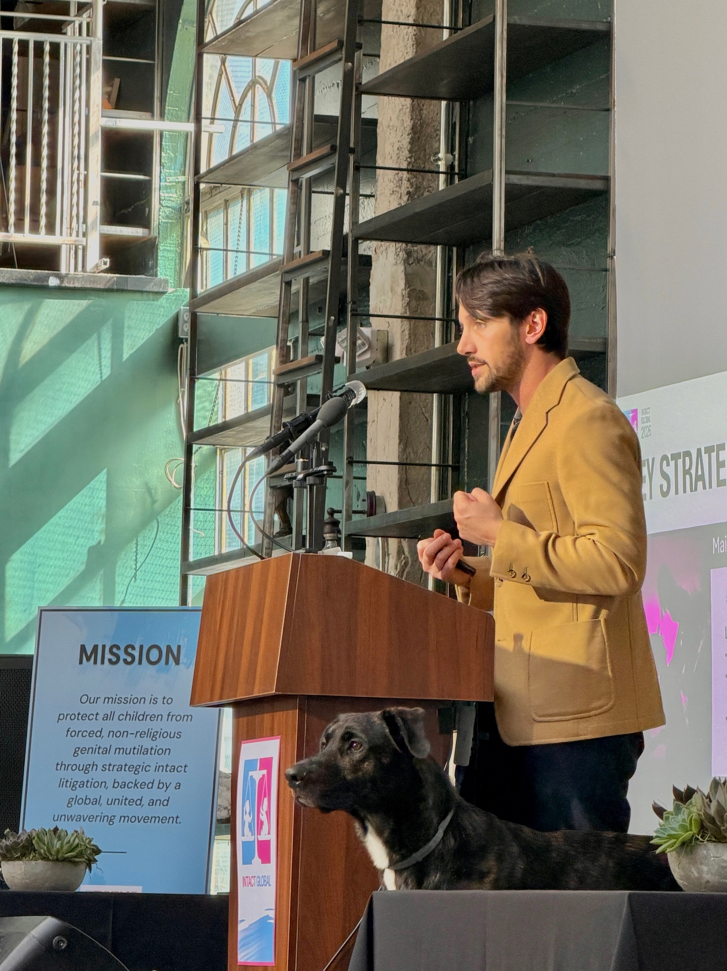 Eric Clopper speaking at an Intact Global strategy conference, with his dog Mountain beside the podium.